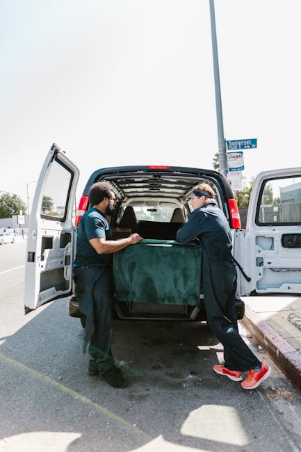 A close-up view of a house removal process inside a property, showing a cardboard box with a packing list or inventory sheet secured under a transparent plastic cover, resting on top of a larger cardb